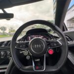Audi R8 multifunctional leather steering wheel with red start engine button and Virtual Cockpit display.