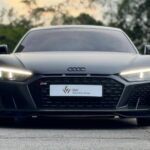 Front profile of a matte grey Audi R8 V10 Performance with signature LED daytime running lights.