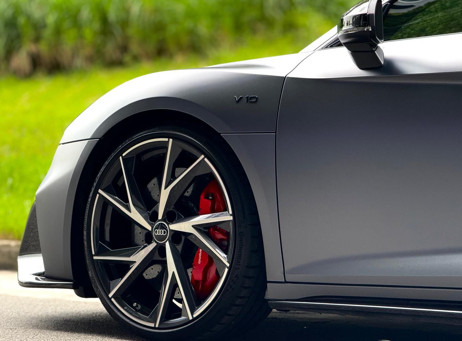 Detailed view of Audi Sport alloy wheels with red brake calipers and V10 badging on the side fender.