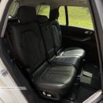 Luxurious 7-seater interior of a BMW X7 with black quilted Merino leather and electric seat adjustments.