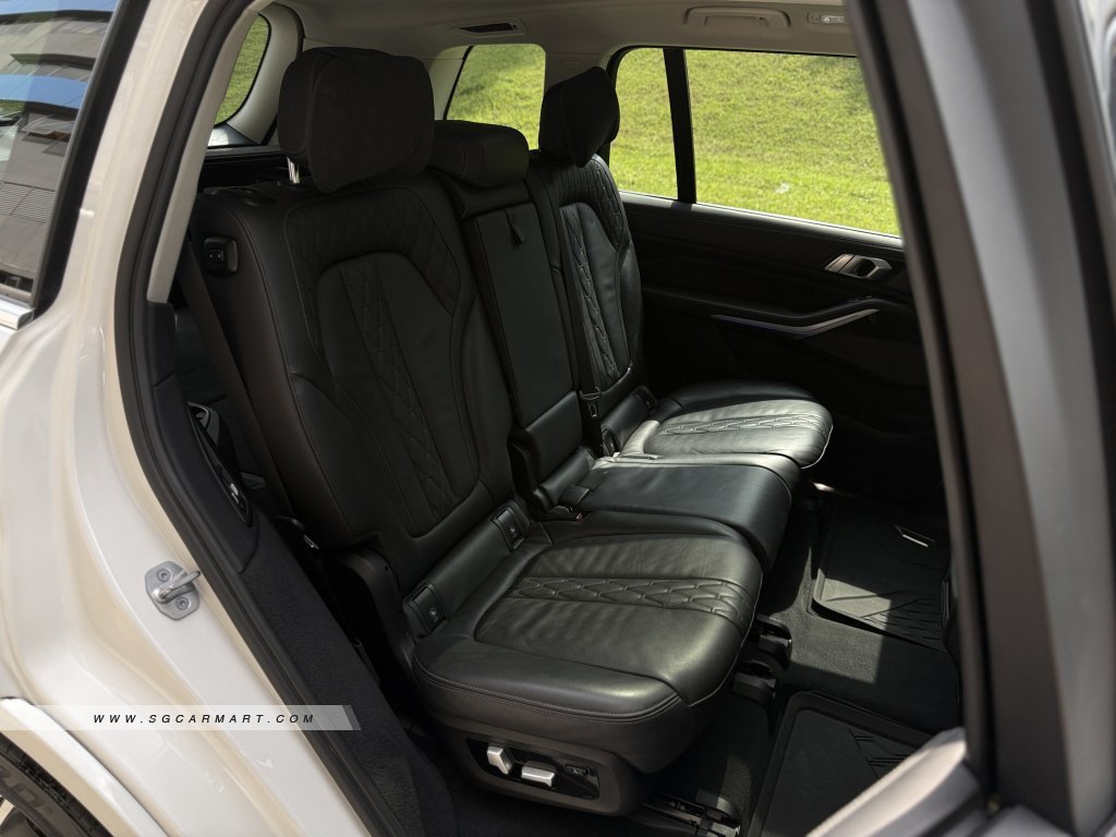Luxurious 7-seater interior of a BMW X7 with black quilted Merino leather and electric seat adjustments.