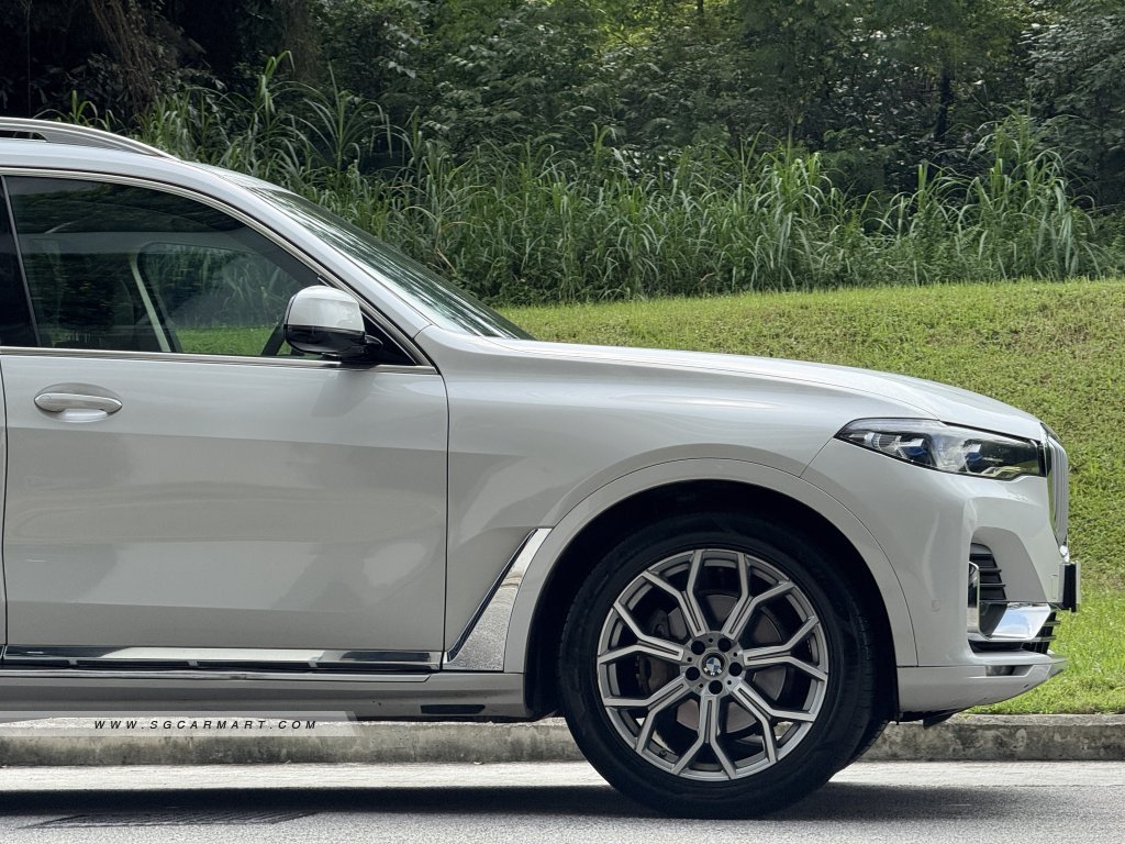 Side view of a white BMW X7 xDrive40i showing alloy wheels and chrome exterior trim.