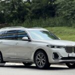 High-angle front view of a white BMW X7 xDrive40i Pure Excellence with the Iconic Glow kidney grille.