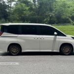 Side profile of a Toyota Noah Hybrid featuring a high-roof design and dual power sliding doors.